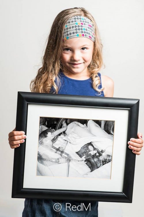 niña con un retrato frente a ella de cuando era una bebé 