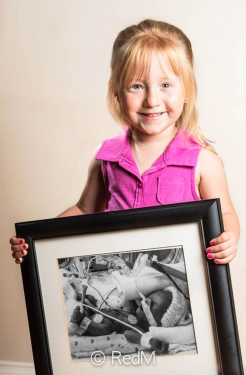 Niña cargando un retrato de ella cuando era una bebé 