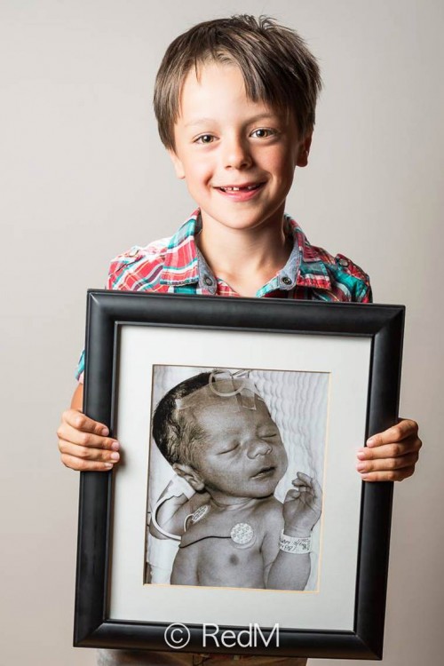 Foto de un niño agarrando un retrato de él cuando era bebé 