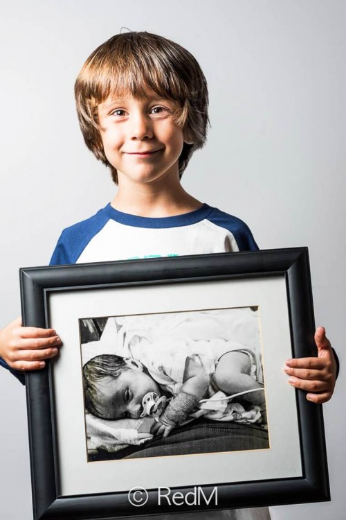 Niño sonriendo y mostrando su retrato de cuando era bebé 