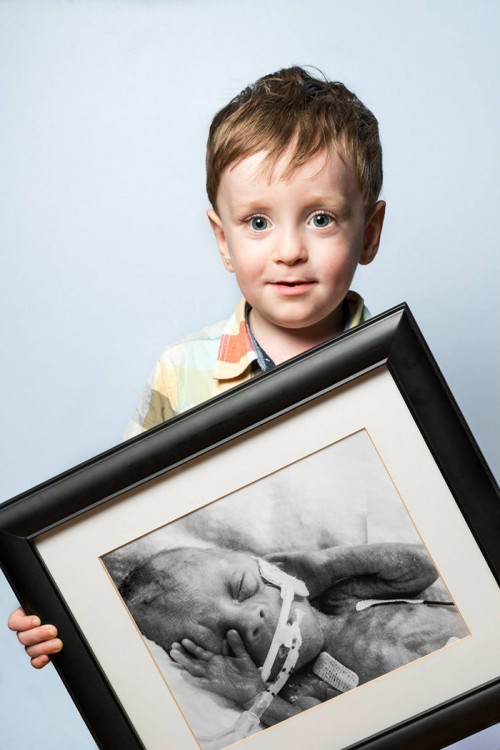 Fotografía de un niño sosteniendo un retrato de él cuando era bebé 