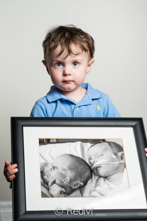 Niño cargando un retrato de él y su hermana gemela cuando eran bebés 
