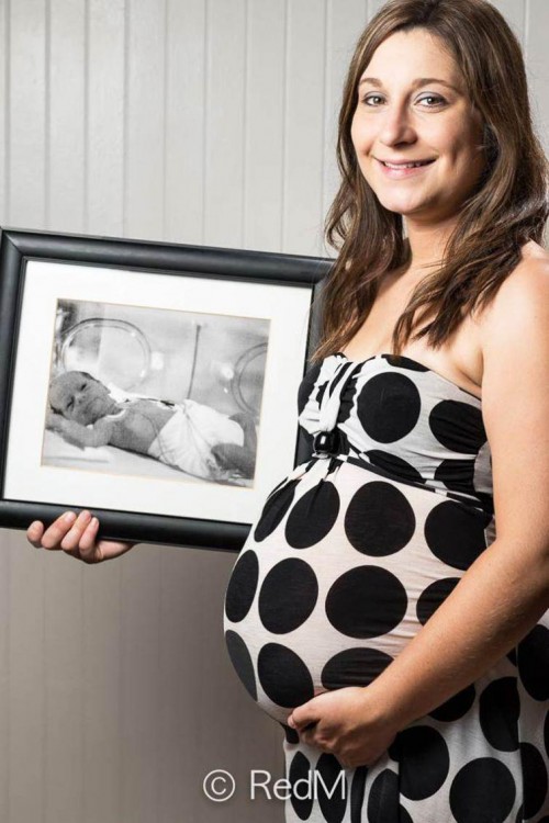 Mujer embarazada con un retrato de ella cuando nació 