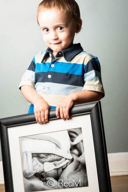 Niño parado sosteniendo un retrato en sus manos 