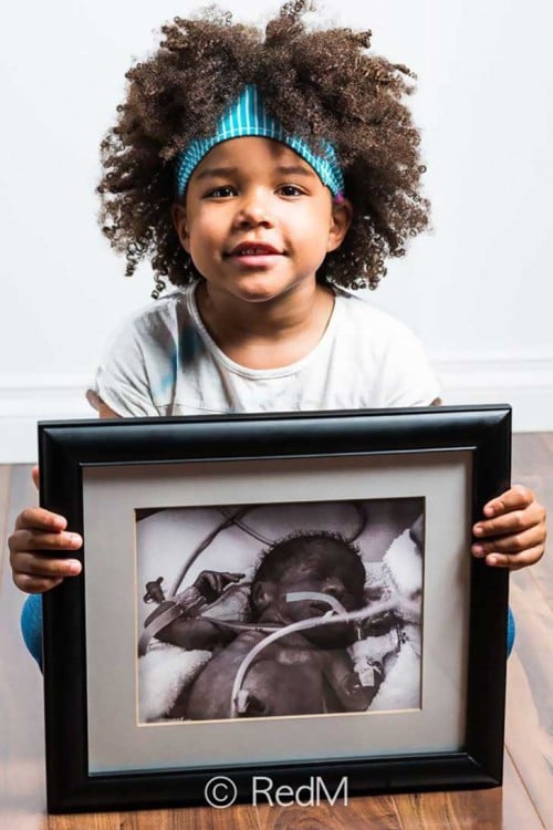 Niña de cabello chino sentada en el suelo sosteniendo un retrato en sus manos 