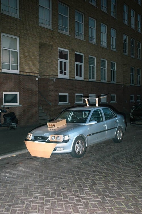 carro en una calle de Amsterdam con unas piezas hechas de cartón pegadas con cinta adhesiva 
