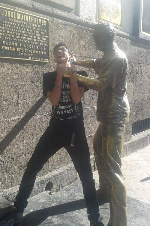 foto de un chico que simula estar siendo estrangulado por una estatua 