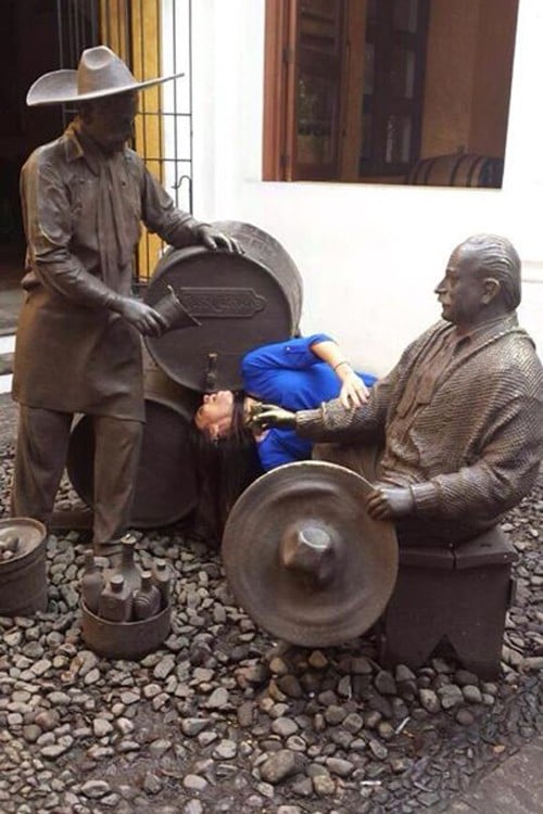 foto de una chica interactuando con unas estatuas simulando que va a tomar cerveza de un barril 