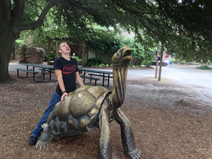 foto de un chico sobre una estatua de tortuga simulando su misma pose 