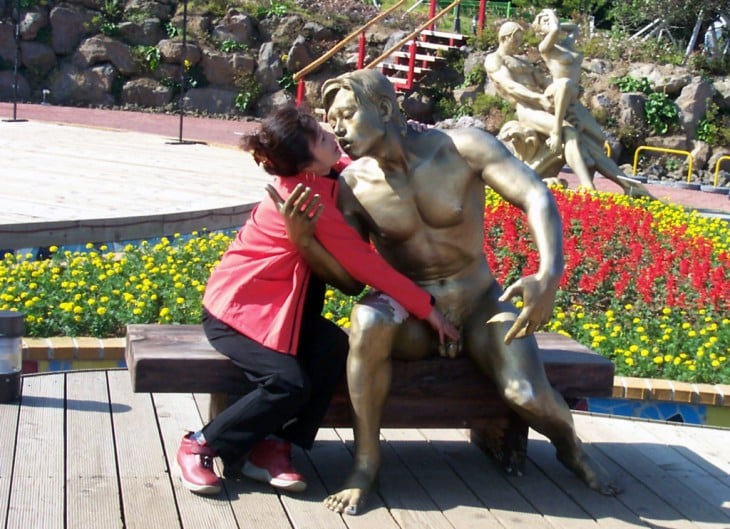 foto de una mujer a un lado de una estatua que parece agarrandole sus genitales 
