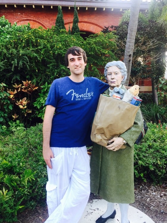 foto de un chico abrazando a una estatua de una anciana con las compras en la mano 