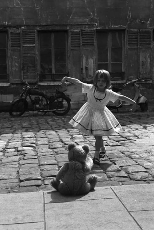 niña bailando frente a su oso de peluche