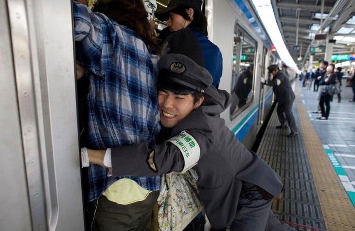 persona intentando acomodar personas dentro de un tren en Tokio, Japón 