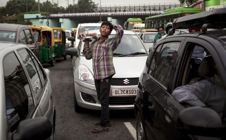 Niño vendiendo cocos a la mitad de la calle en Nueva Delhi, India. 