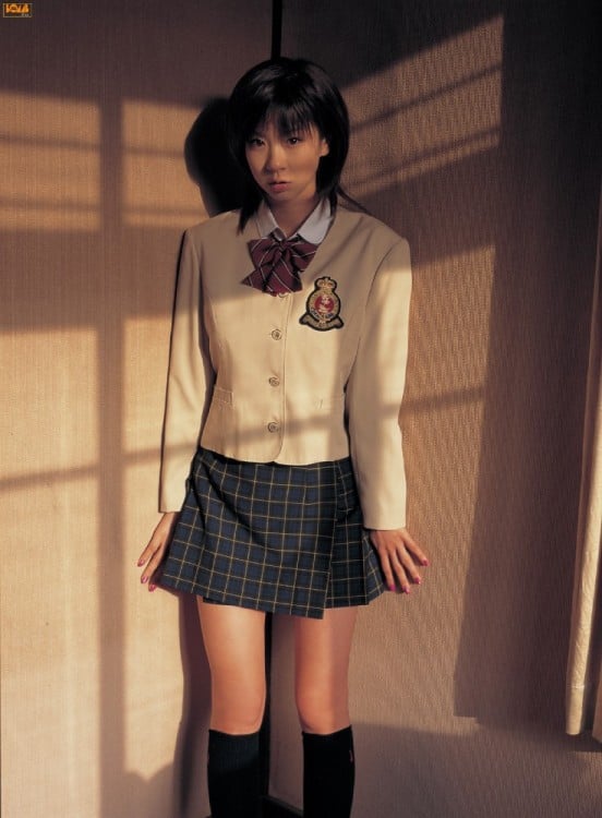 chica con uniforme de colegiala en la esquina de un cuarto 