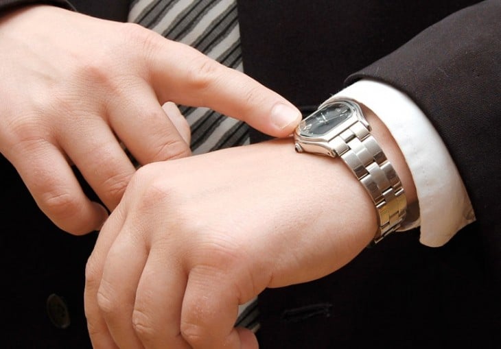 manos de una persona señalando un reloj con una mano 