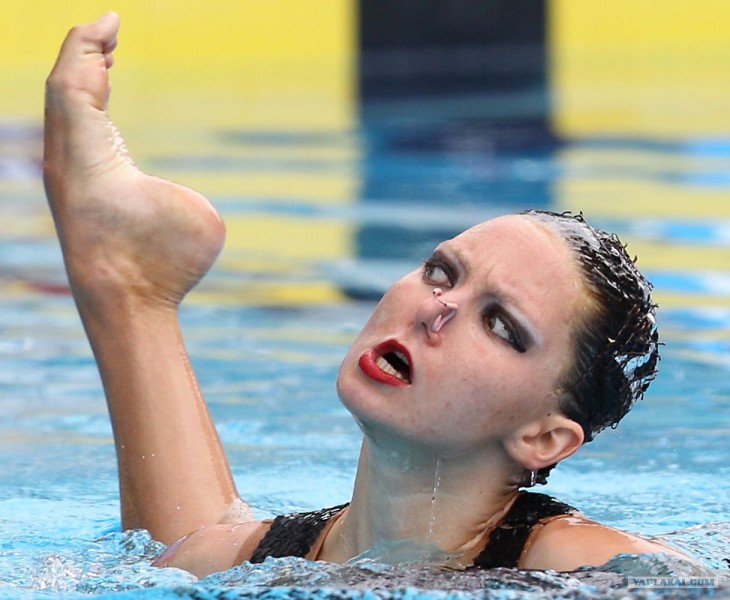 chica dentro de una piscina con un pie a un costado de su cabeza 