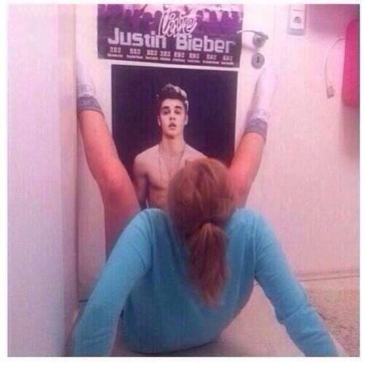 mujer haciendo el ridiculo en un poster de justin bieber