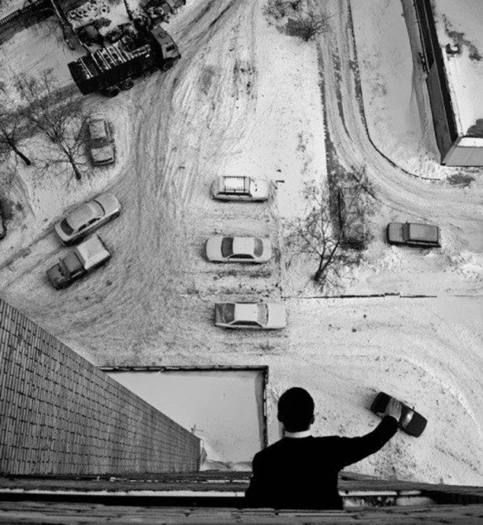 hombre jugando a los carritos con carros de verdad desde el piso de su edificio