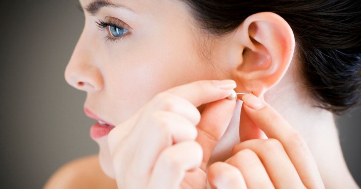 mujer poniéndose un arete en el oído 