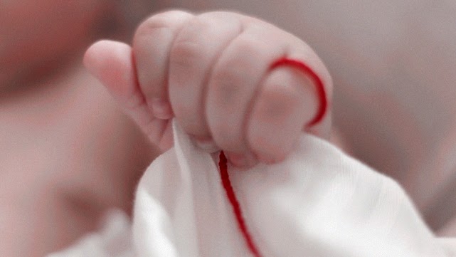 mano de un bebé con un hilo rojo atado a su meñique 