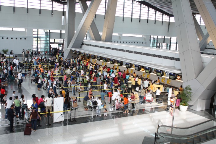 filas de personas con sus equipajes dentro de un aeropuerto 