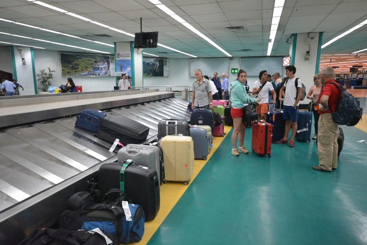 personas recogiendo su equipaje después de pasar por los rayos x 