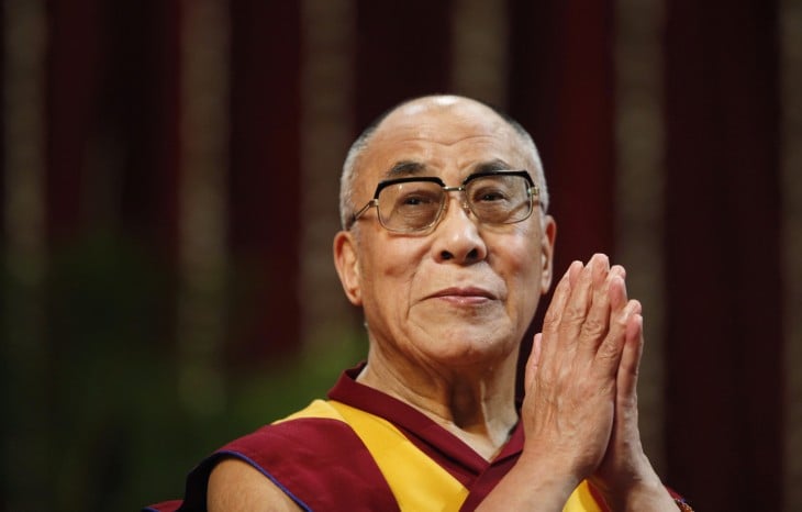 Dalai Lama con las manos juntas como si estuviera haciendo oración 
