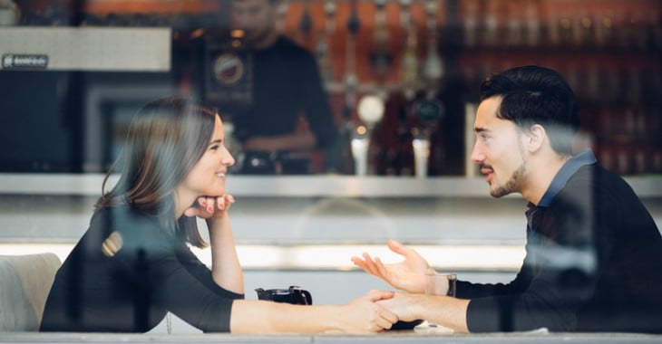 un hombre y una mujer sentados en la mesa de un restaurant platicando tomados de la mano 