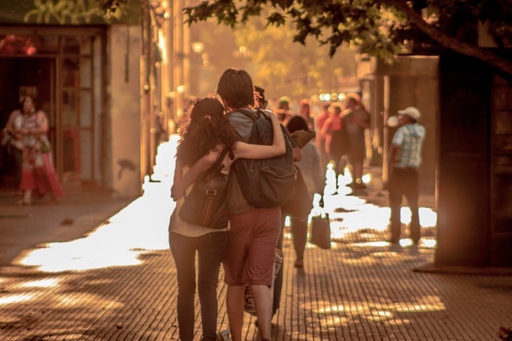 Una pareja de novios abrazados caminando por una calle 