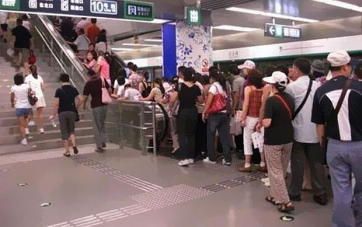 Personas haciendo fila para subir por las escaleras eléctricas 