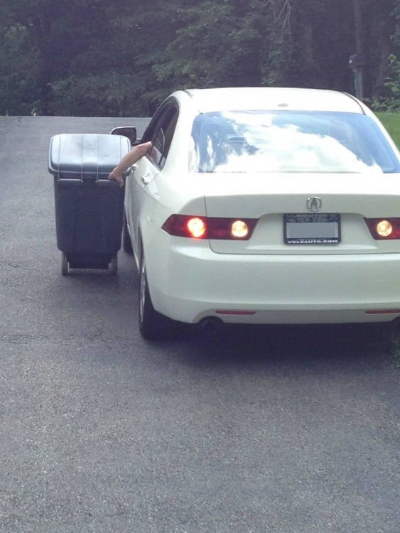 persona llevando un bote de basura desde la venta de un coche 