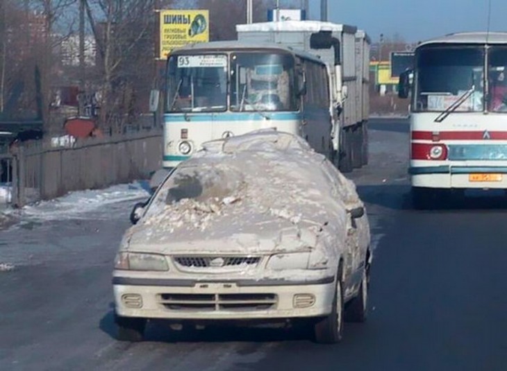 coche lleno de nieve transitando por una calle 