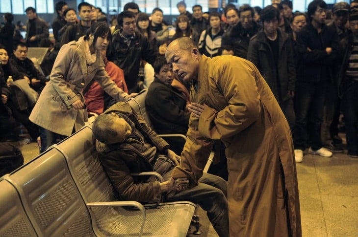 monje rezando a un hombre muerto dentro de una estación de tren en China 