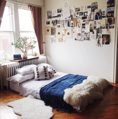 un colchón en el suelo en una recámara con muchas fotos pegadas en la pared 