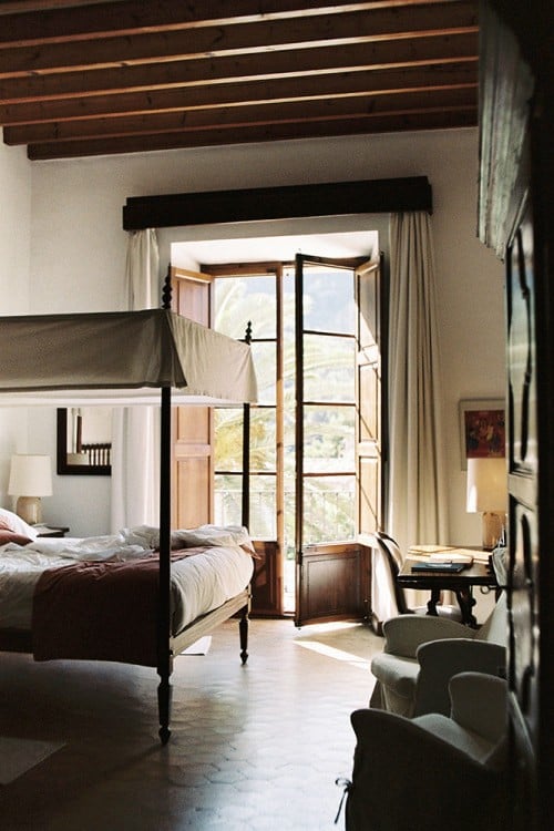 habitación con una cama que tiene protección en la parte superior, sillones y una mesa de trabajo cerca de una ventana 