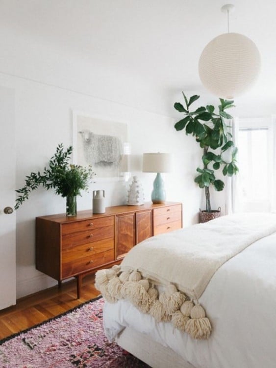 habitación donde solo se ve una parte de la cama y un mueble con unas plantas 