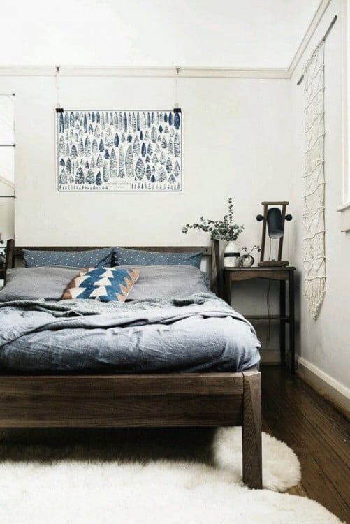 cama dentro de una habitación en color blanco con un cuadro encima de la cama 