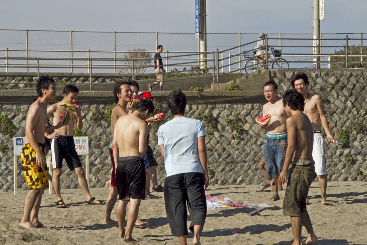 chicos Japoneses comiendo sandía en una playa 