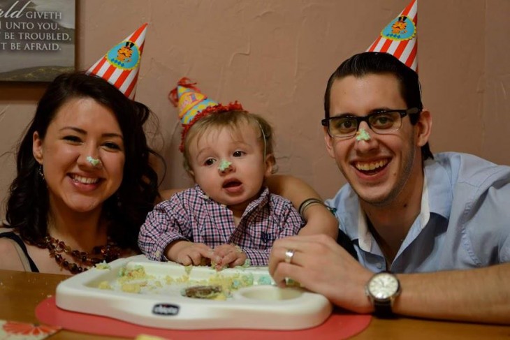 una pareja de esposos festejando a su hijo con un pastel 