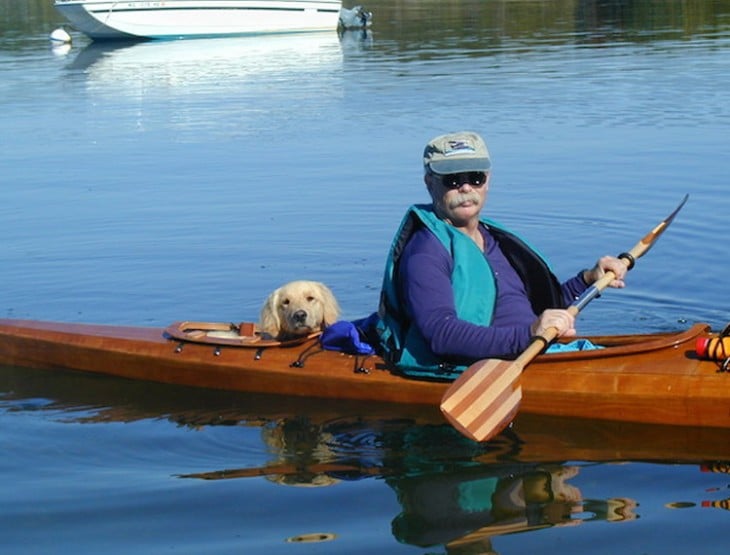 foto de un hombre y un perro dentro de un kayak en un lago 