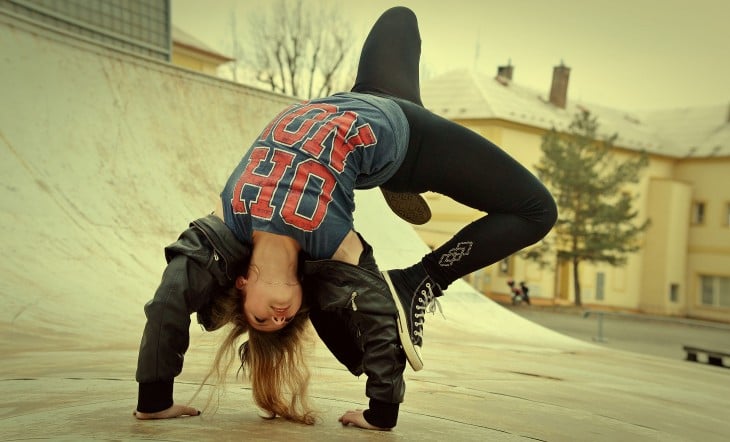 una chica bailando break dance en una calle 