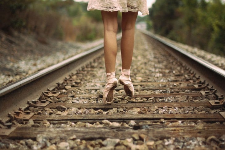 pies de una bailarina de ballet a la mitad de unas vías de ferrocarril 