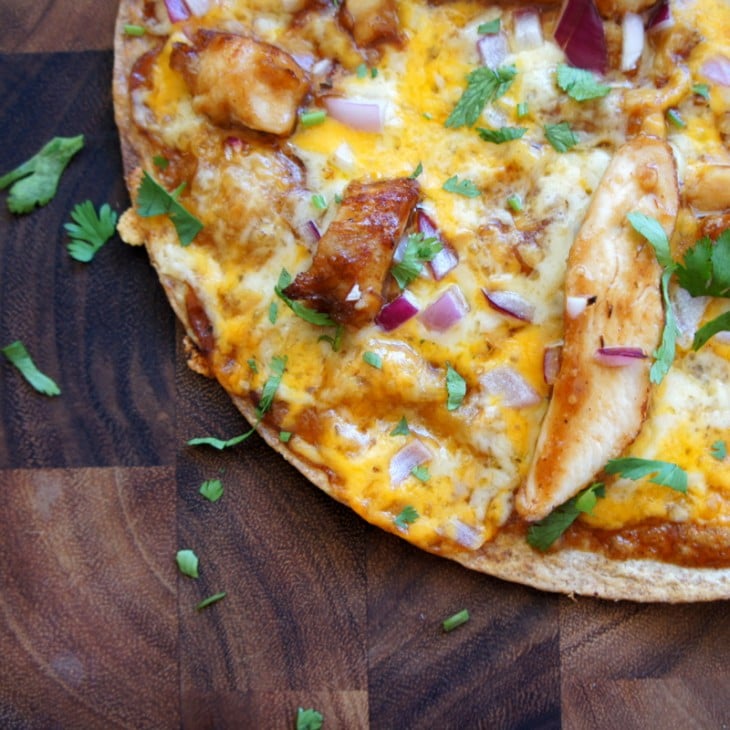 pizza hecha con una base de tortilla de maíz cubierta con pollo a la BBQ 