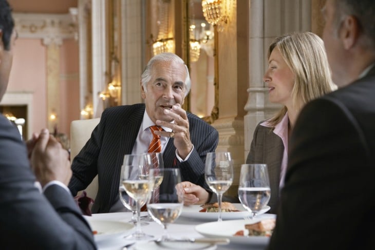 hombre hablando durante una cena rodeado de personas 