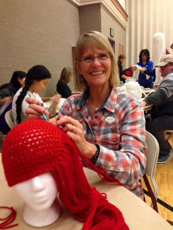 mujer tejiendo una peluca con hilo en color rojo 