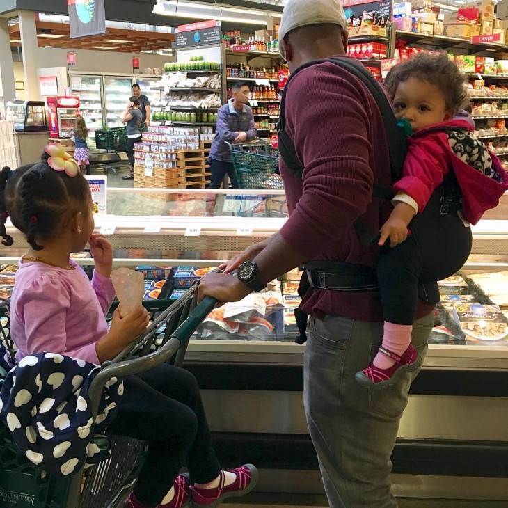 papa cuidando a sus ddos hijas mientras hacen las compras