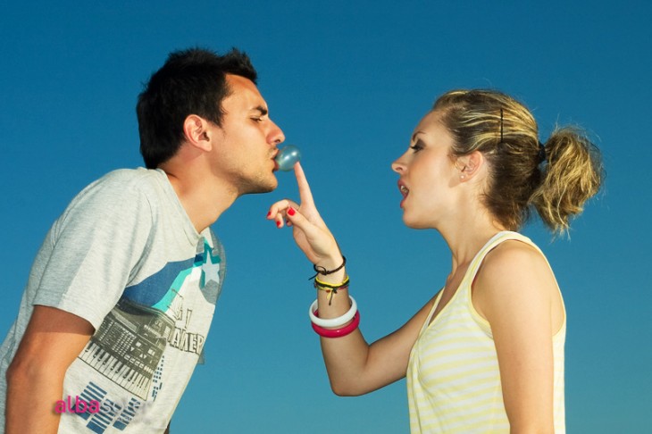 chica intentando romper una bomba de chicle a un chico 