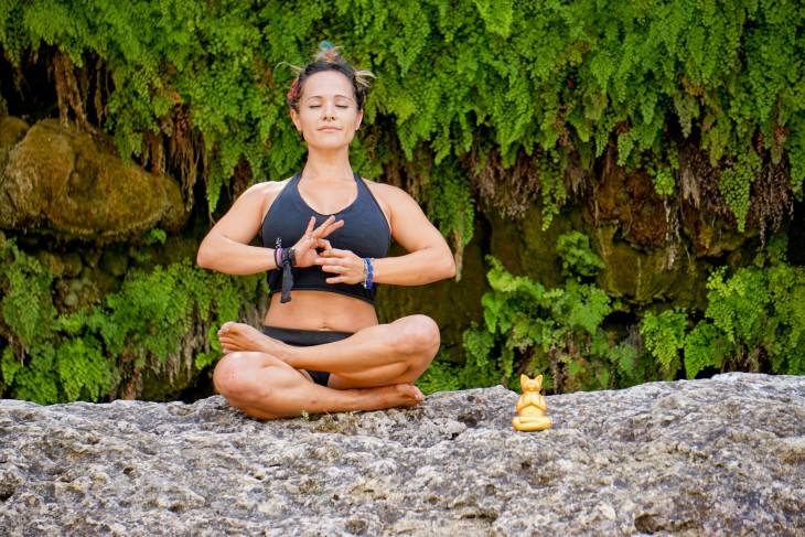 mujer practicando yoga al aire libre sobre una gran piedra 