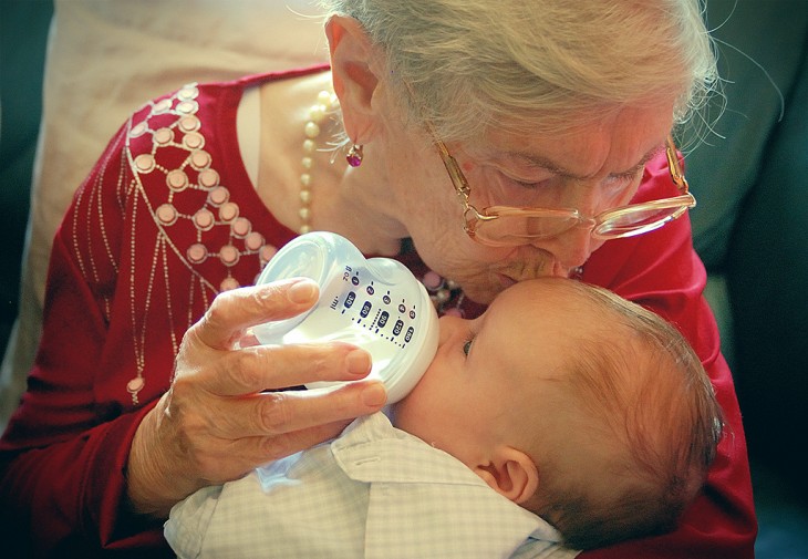 Abuelita con su nieto en sus brazos dando un beso en su frente 